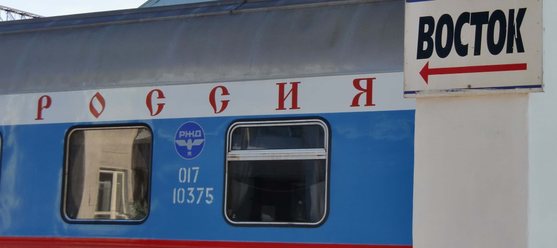 Moskau-Wladiwostok. Transsib. Russischer Eisenbahnwagon mit kyrillischer Schrift "Rossia" und Schild "Bostok"-Richtung Osten